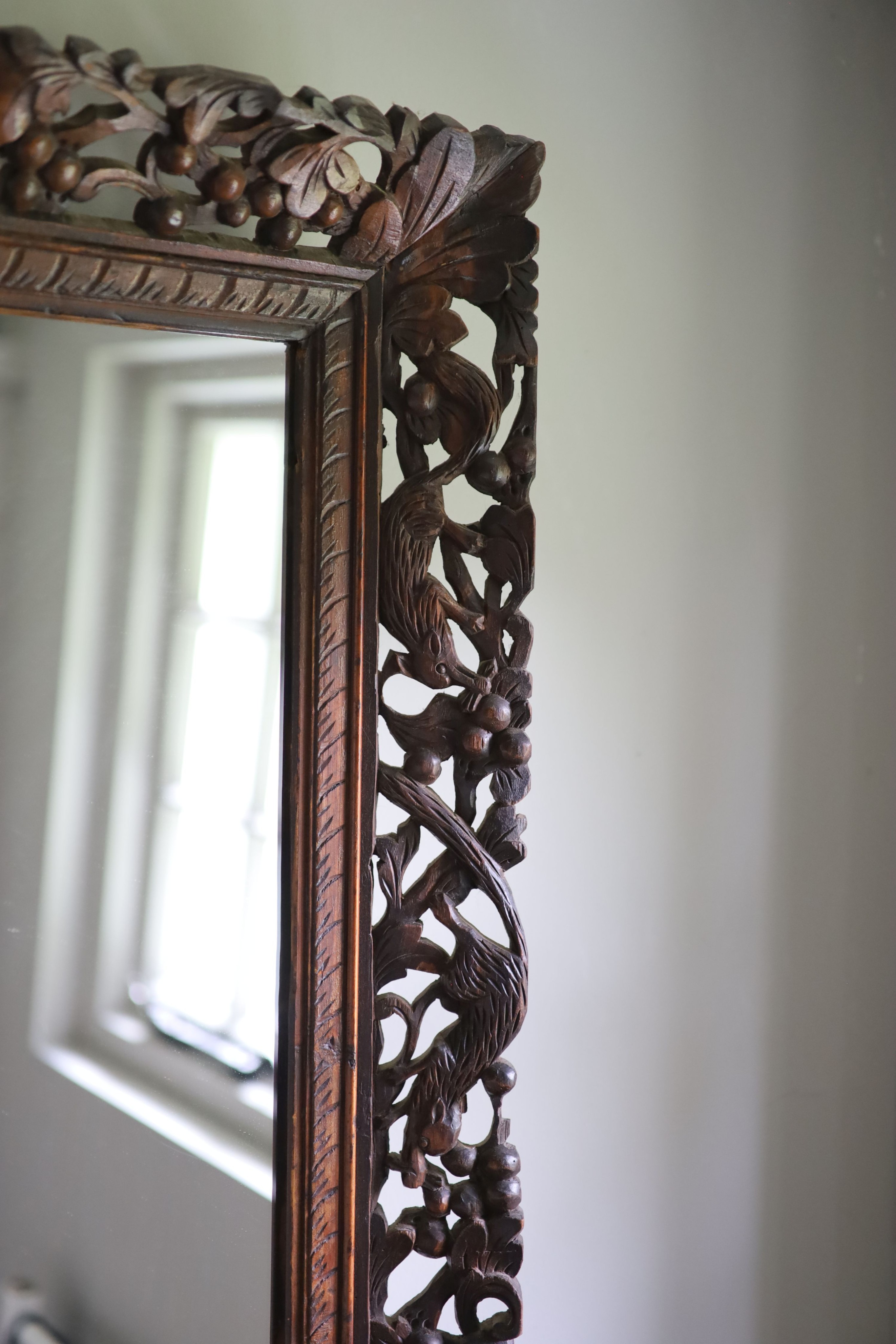 A Continental hardwood wall mirror, carved and pierced with squirrels and fruit, width 77cm height 63cm